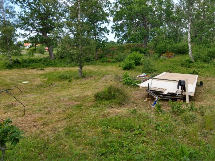 Nytt golv under konstruktion i utomhusmiljö med slyklippt gräsmatta och träd i bakgrunden.