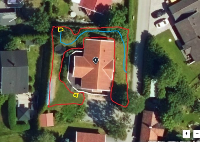 Flygbild av hus och trädgård med markerade linjer för robotgräsklipparens begränsning och guide samt laddstationens placering.