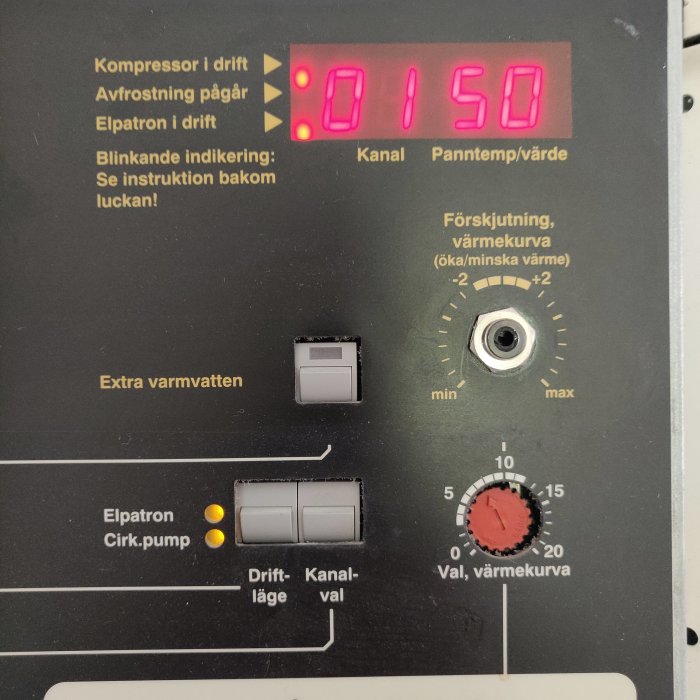 Värmesystemskontrollpanel med digital display visande '0150', knappar för 'extra varmvatten', och blinkande lampor.