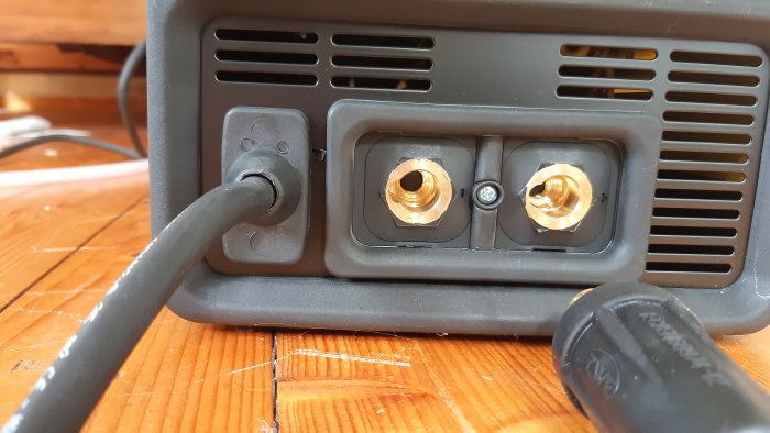 En svetsmaskins bakpanel med en ansluten kabel och två ouppkopplade uttag märkta för gas respektive no gas.