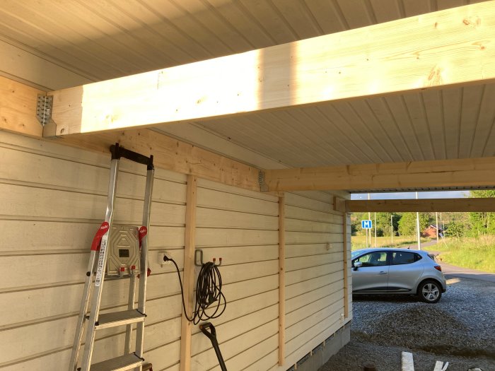 Tillfälliga balkar på 45x220 mm monterade ut från en befintlig vägg i ett byggprojekt, med en stege under och en bil i bakgrunden.