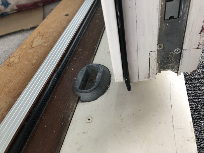 En altandörr som hänger snett med synliga metallbleck och gångjärn, vilket indikerar problem med stängning.