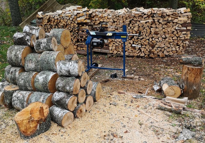 Vedklyv vid vedstapel och stockar redo att klyvas.