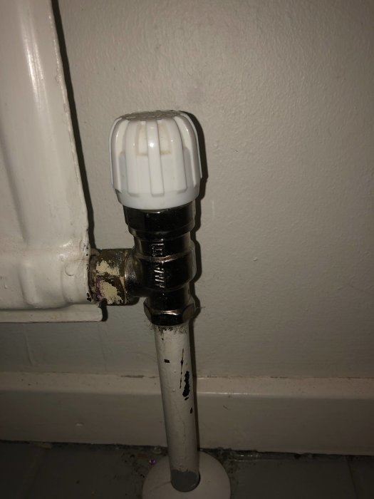 Närbild på en äldre radiatorventil märkt VV10 utan förinställning, monterad på radiator i hus från 1966.