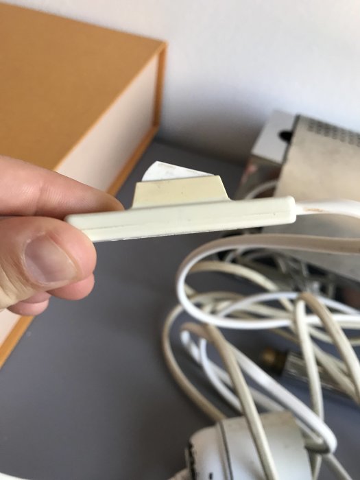 Hand som håller en gammal vit strömbrytare på en sladd mot en oskarp bakgrund.