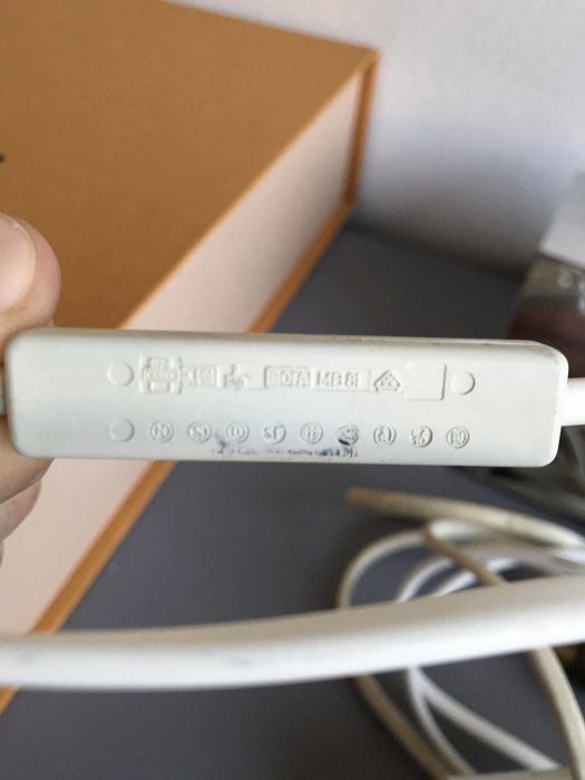 Hand håller en vit strömbrytare med kablar för skrivbordslampa, söker identisk ersättning.
