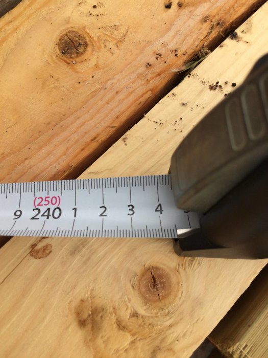 Måttband som visar höjden på en träregel, ungefär 2440 mm, för byggprojekt.