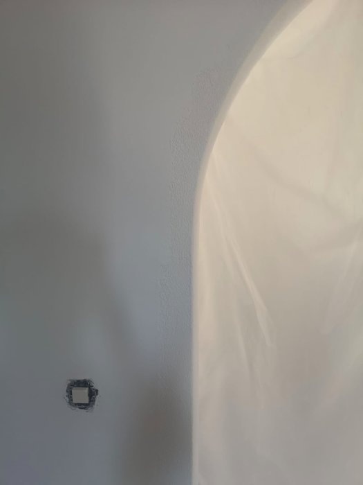 Nyrenoverad hall med ett slätt målat valv och en synlig del av grov struktur kvar vid kanten.