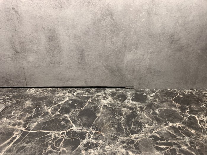 20 centimeters gap between a grey concrete wall and a black marble counter.