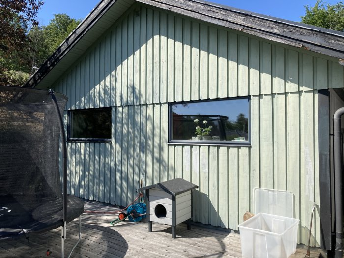 Gavelspetsen på ett garage med vertikal grön panel och fönster inför fasadbyte utan isolering.