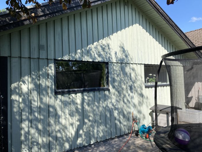 Garagefasad med stående panel och gavel redo för renovering med ny, liggande panel.
