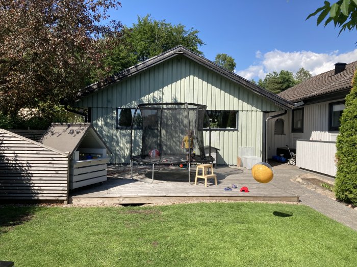 Garage och hus med grön panel och fasadbyte nära slutförande, verktyg och leksaker på gården.