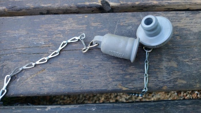 Isärtagbar gammal propp med kedja på träbänk.