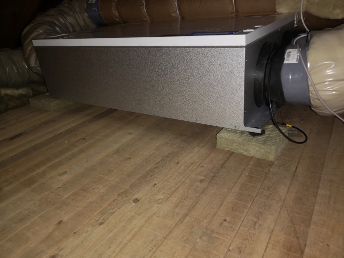 Ventilationsenhet monterad på isoleringskiva för vibrationsdämpning på vindsbjälklag.