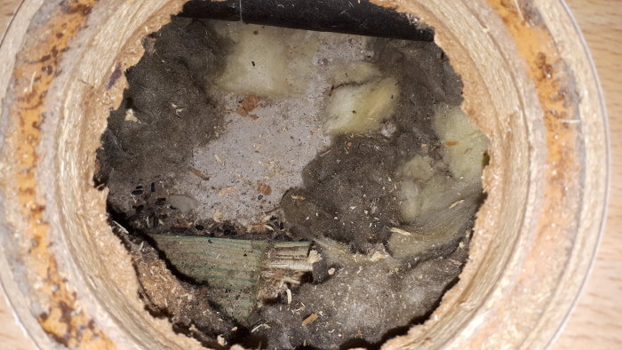 Inspektionshål i golv visar del av grön spikregel och isolering, svårbedömd syll syns.