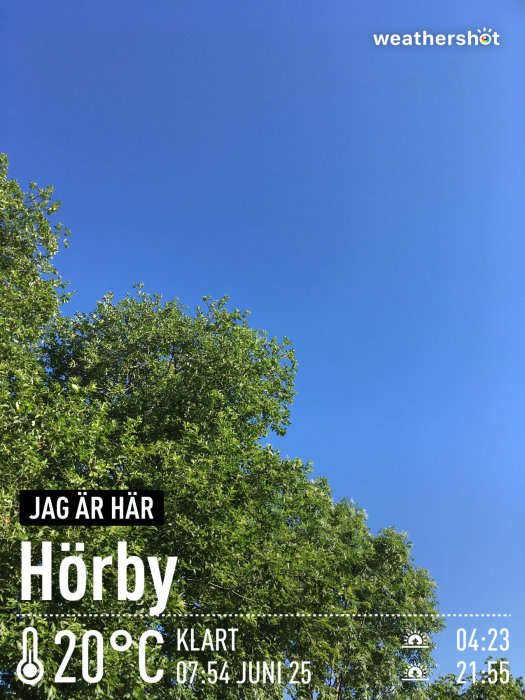 Klart väder i Höör med temperaturangivelse på 20°C, datum och tid under en blå himmel och trädtoppar.