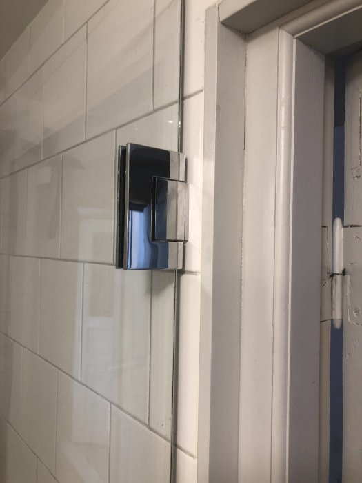 Kant på vägg med kakel bredvid ljusbrytare, intill en dörrpost, ej våtzon.