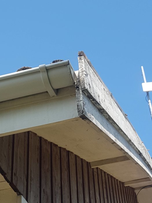 Takfot med två träbrädor och en stupränna sett från sidan på ett hus.
