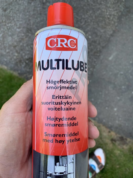 Närbild av en hand som håller en flaska CRC MULTILUBE högeffektivt smörjmedel.