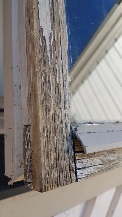 Slitet och torkat trä på ett garagefönster som behöver underhållsmålning.