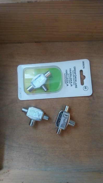 Överskottsgrå metallfästen för 5 kronor spridda på träyta, delvis i originalförpackning.