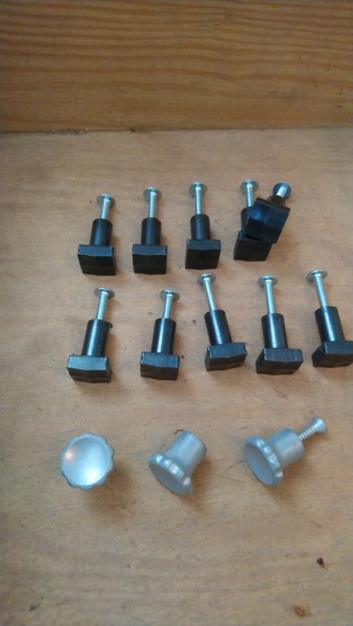 Samling svarta och silverfärgade knoppar på träyta, avsedda för byrå eller kökslucka.