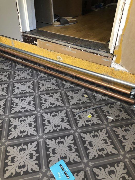 Renoverad tvättstugas golv med framträdande rör nära dörrtröskel som behöver en ny trappa.