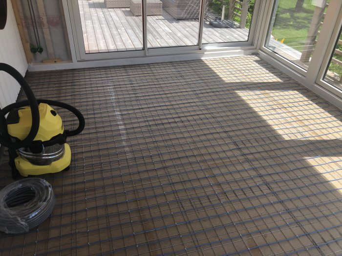 Uterum med armeringsnät på golvet, redo för flytspackling, dammsugare och kabelrulle syns.