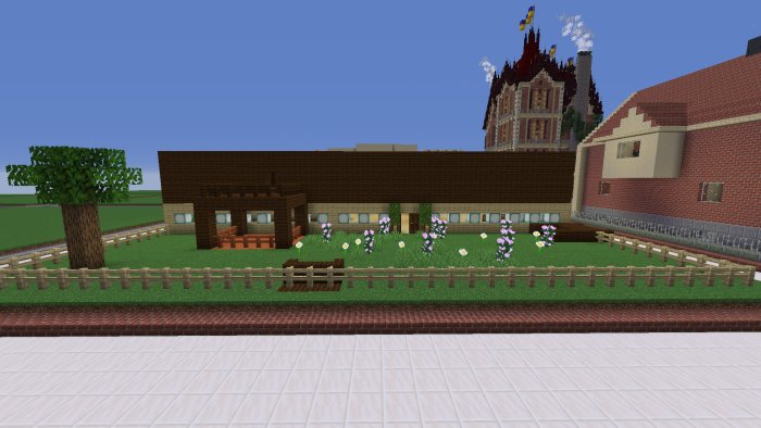 Vy över ett Minecraft-bygge med flera olika hus, träd och blommor i förgrunden bakom ett staket.