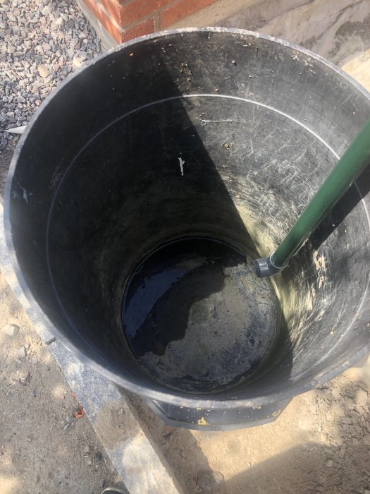 En nästan tom regntunna med lite vatten i botten inspekteras efter skyfall.