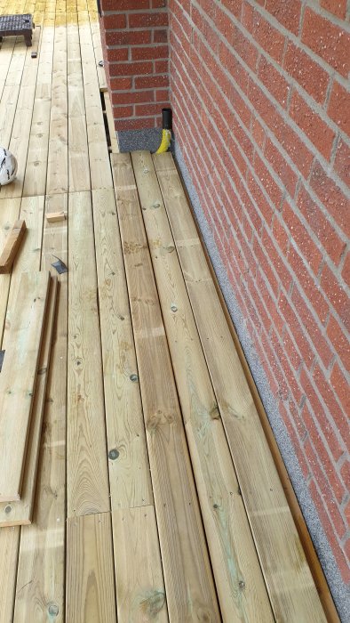 Trätrall intill en tegelvägg med synlig springa där skräp kan samlas.