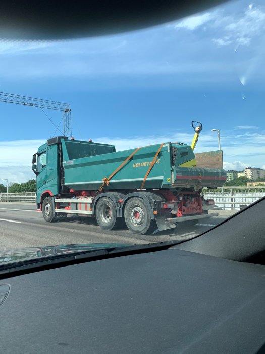 Lastbil med grönt flak och säck med 400kg padda på Essingeleden, säkrad med orange spännband.