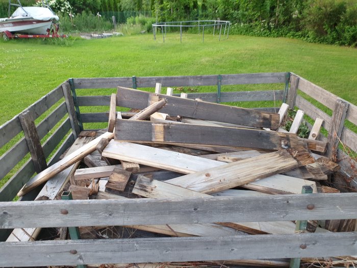 En upprutten badtunna i delar på en släpvagn, redo att kasseras, med grön gräsmatta i bakgrunden.