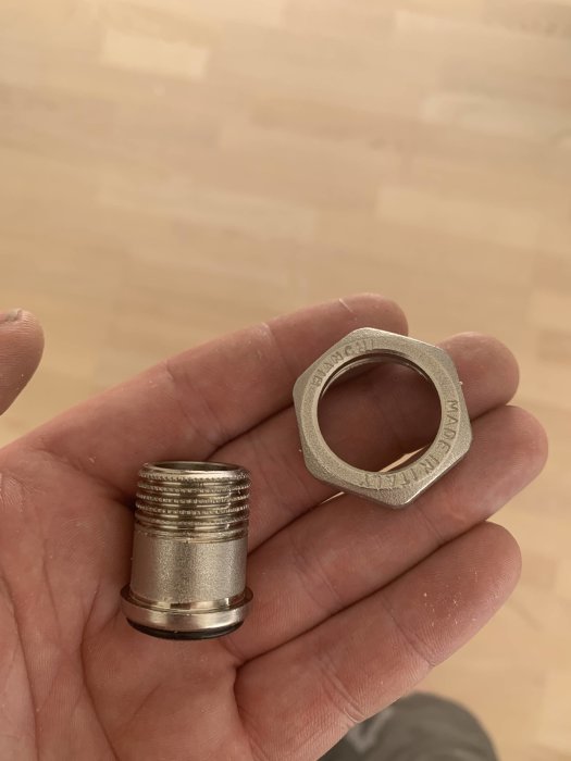 Hand håller en demonted LK minifördelarkoppling och en löstagbar flänsring.