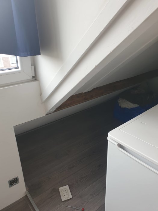 Takvåning med lutande tak, synligt bjälklag, och golvyta som inte når taket på dess vänstra sida.
