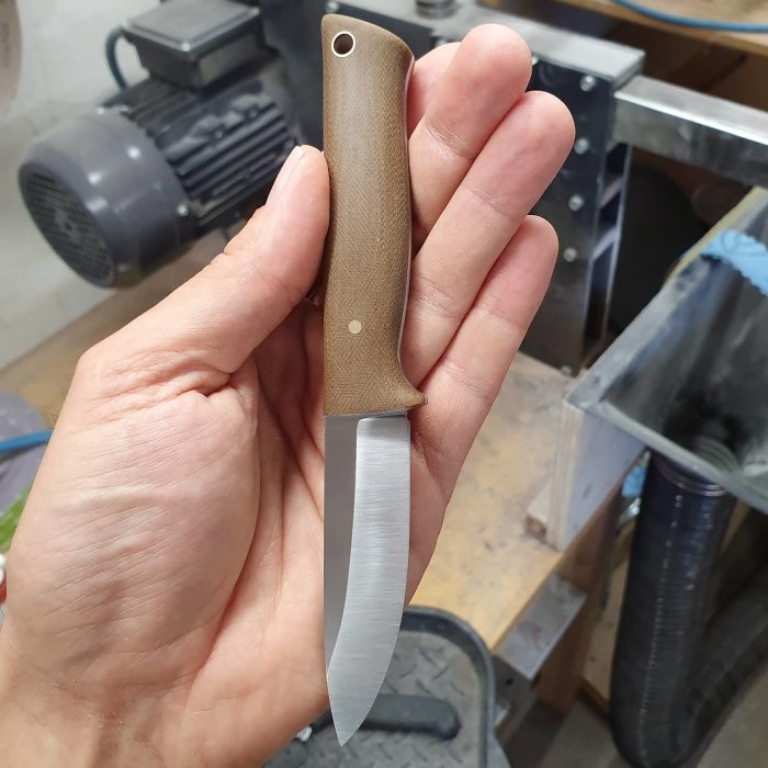 Hand håller en handgjord kniv med micartahandtag och 14C28N stål, 170 mm total längd.