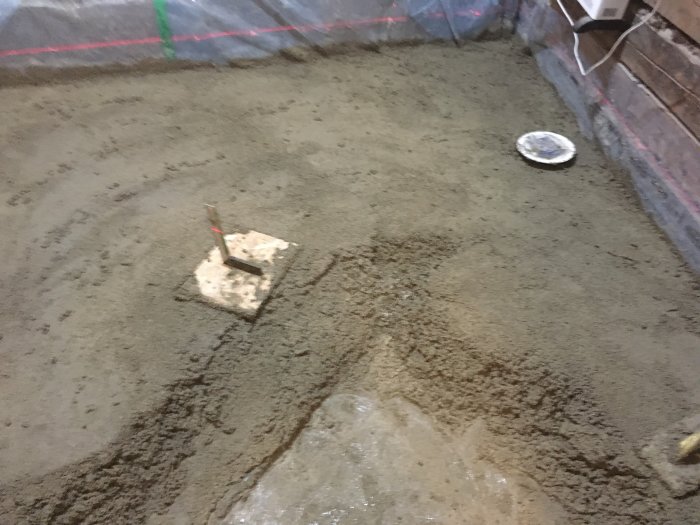 Grävt gammalt pannrum med EPS-isolering underlag, flytspackel och avloppsrör synligt, i byggprocess.