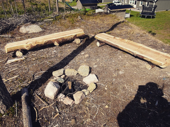 Två hemgjorda träbänkar skapade med alaskan sågverk vid en eldstad utomhus.