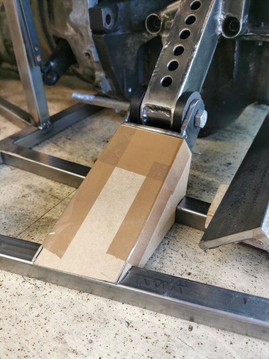 En CAD-modell av en komponent, skapad i kartong, placerad på ett metallramverk i en verkstad.