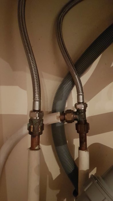 Två metallslangar anslutna till rör med en borttagen rörstump och en synlig gänga.