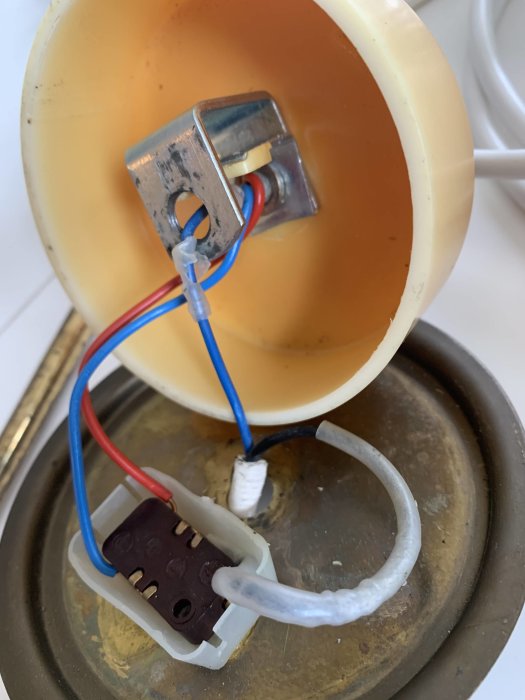 Begagnad Bumling-lampans insida med öppen tryckströmbrytare och flera elektriska ledare.