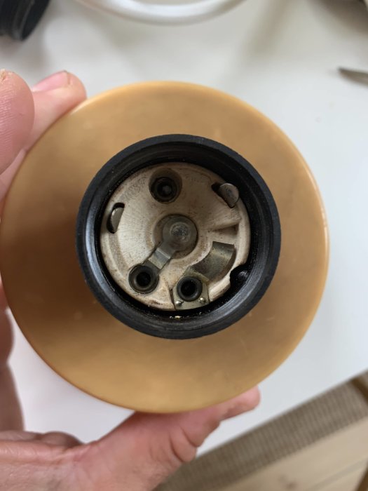 Närbild på en person som håller i en lampa med synlig sockel och elektriska kontakter.