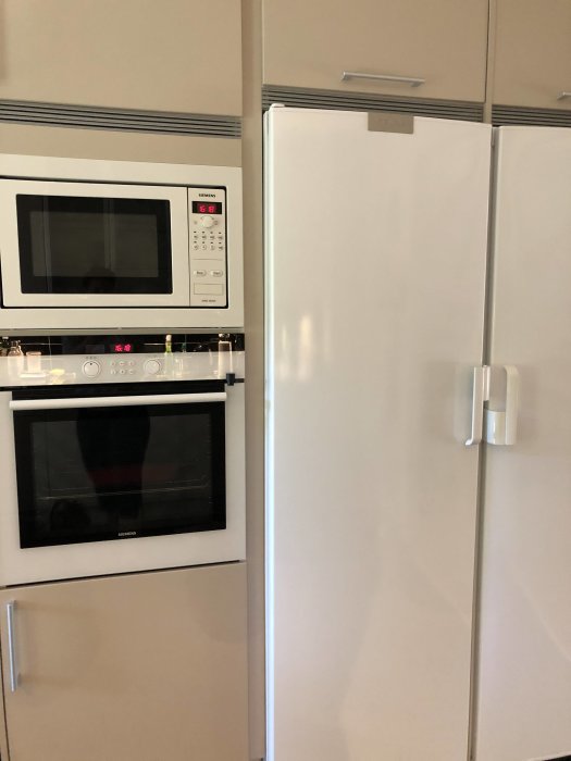 Siemens vitvaror i ett kök: mikrovågsugn ovanför ugn och bredvid ett kylskåp.