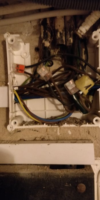 Oordnade gamla elkablar kopplade i två plasthöljen där en tidigare elcentral satt, potentiell felaktig installation.
