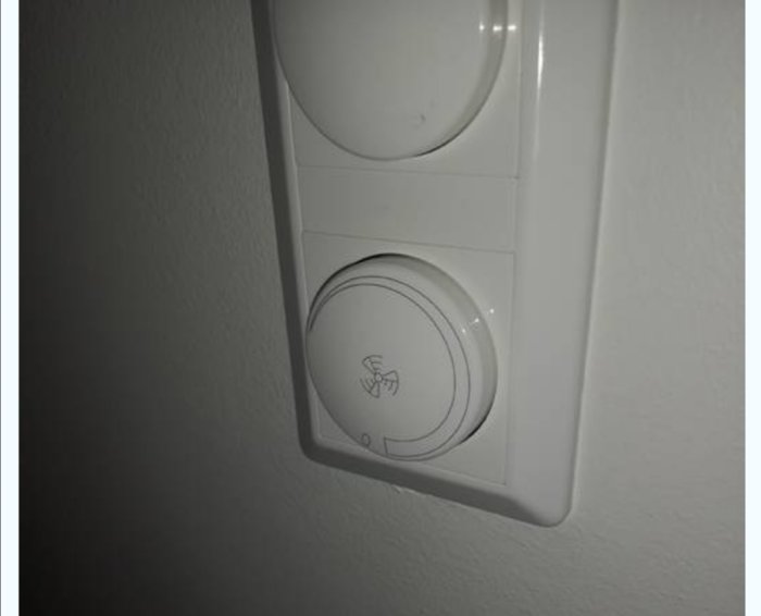 Väggmonterad termostat eller kontrollenhet för ventilationssystem i ett hem.