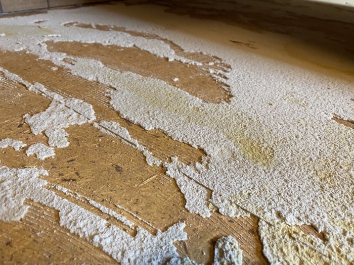 Spånskivegolv med rester av skumgummi efter borttagen matta, förberedelse för laminatgolv.