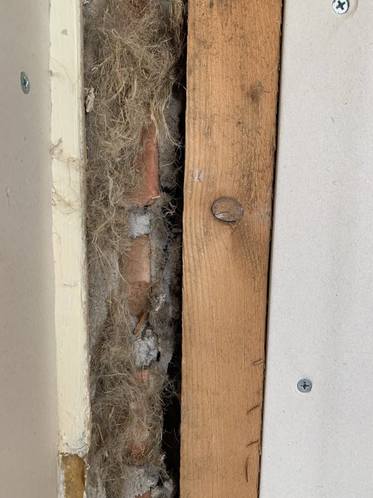 Glipa i vägg med synliga isoleringsmaterial och murtegel bakom borttagen garderob.