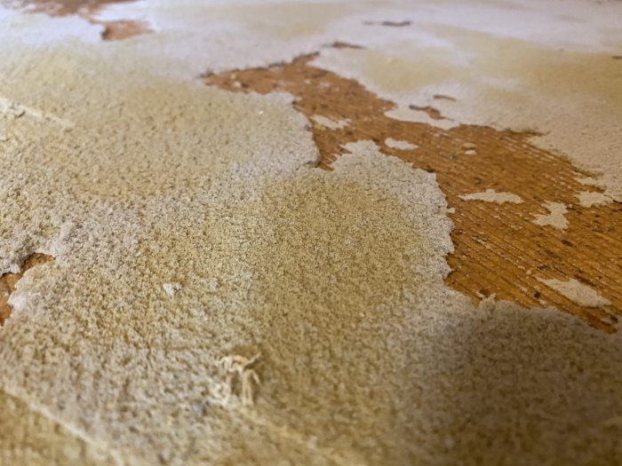 Golv med skumgummirester och spånskiva efter borttagen matta, diskussion om laminatgolvinstallation.