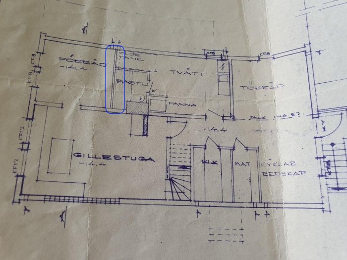 Arkitektritning av källarvåningen i ett hus med markerad vägg i blått.