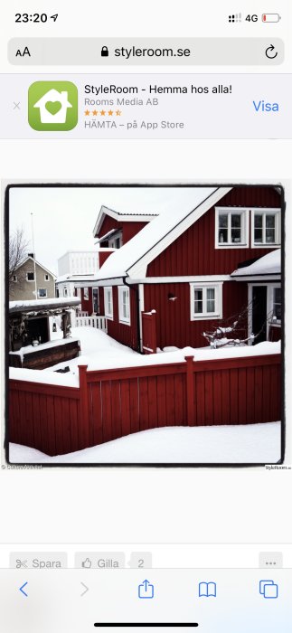 Rött trästaket framför hus med snötäckt trädgård och röda husväggar.